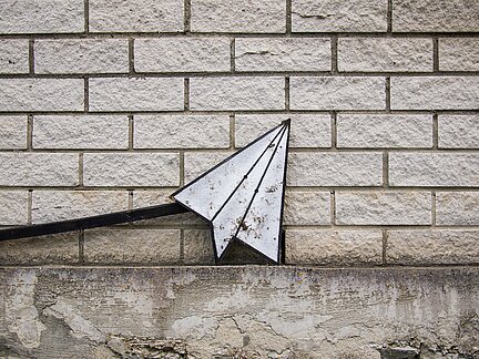 paper airplane against a brick wall
