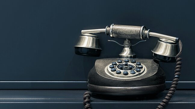 Image of a black old fashioned telephone with a dialler. 