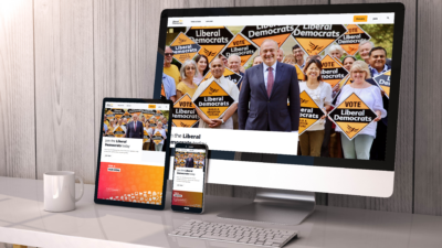 The Liberal Democrats home page on a desktop screen, a tablet, and a mobile phone. On the home page a smiling Ed Davey stands in from of party members holding "Vote Liberal Democrats" stakeboards.